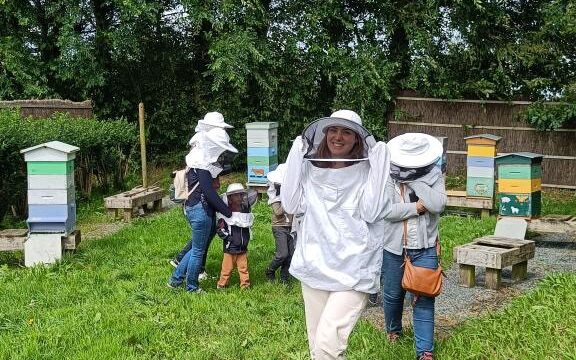 Visite près des ruches avec chapeau de protection pour observer les abeilles